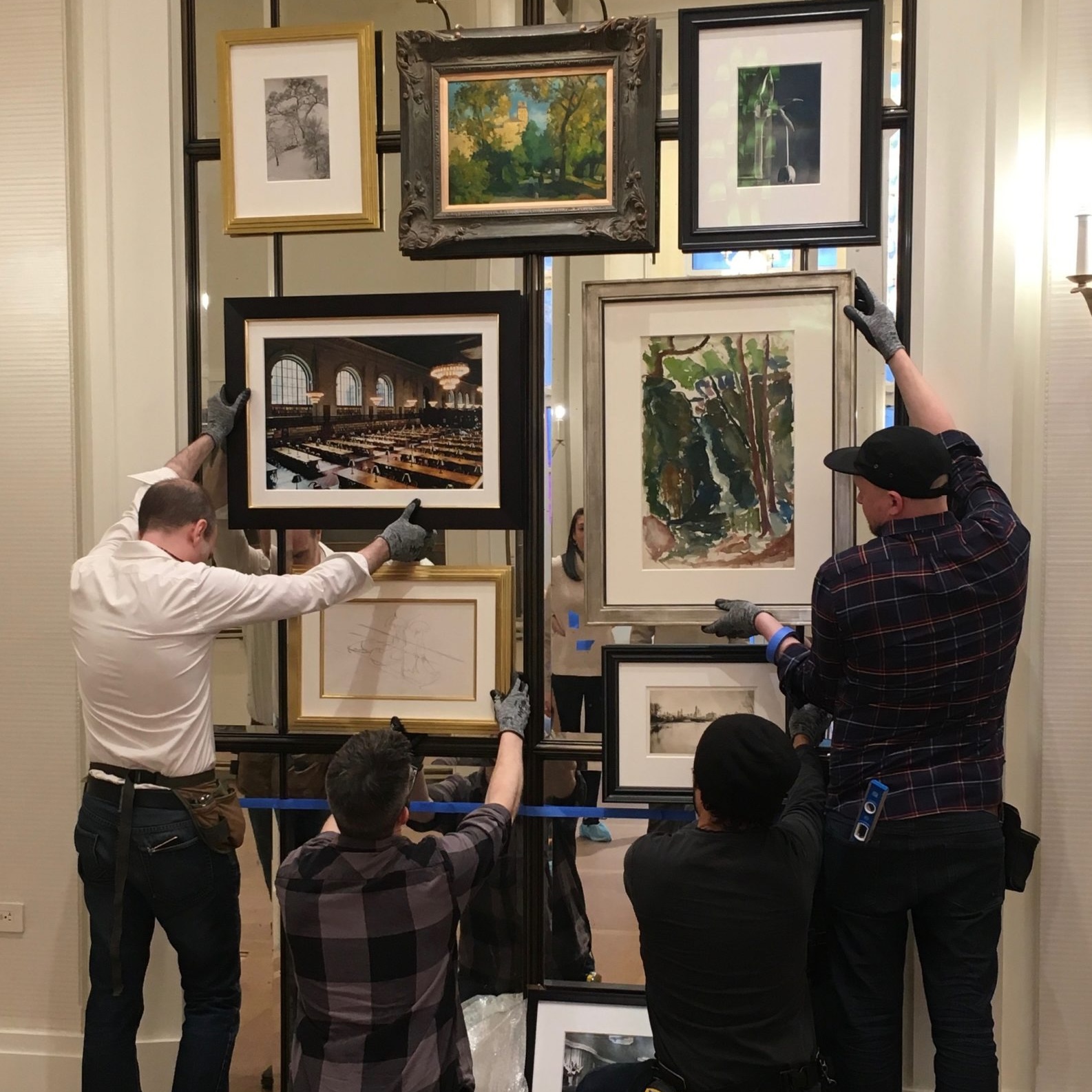 Trained art handlers placing salon wall on mirrored surface